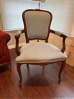 Front view of armchair showing light blue upholstery with subtle motif and carved wood frame with floral details.