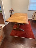 Full side view showing table extended on red rug with wood floor.