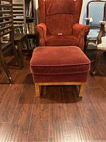 Front and side view of the red velvet/velour fabric ottoman with wooden legs showing wear and condition.