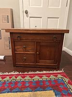 Front view showing three drawers and one cabinet door with original metal ring pull hardware on a wooden side table.