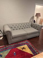 Front view of grey-blue tufted sleeper sofa showing overall style and condition