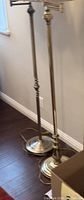 Two brass swing arm floor lamps without shades, showing bases and stands, highlighting different base and stand designs.