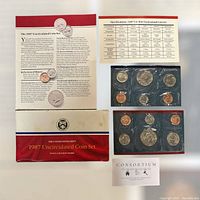 Full view of the 1987 United States Mint uncirculated coin set showing the coins in plastic holders, original folder, and detailed printed informational sheets explaining coin specifications and historical notes.