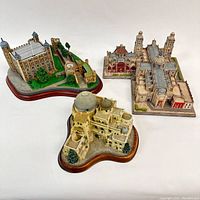 Photo shows three models of historic places, each placed on a shaped base with landscaping details. Models represent detailed architecture of historic buildings.