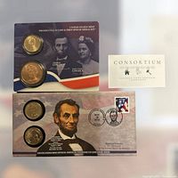 Two U.S. Mint collector sets displayed, one Presidential 1 Coin and First Spouse Medal set with Abraham and Mary Todd Lincoln portraits, the other an Official American Presidency 1 Coin Cover Series with Abraham Lincoln.
