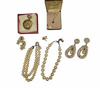 All items together - pocket watch in a red box, amethyst pendant necklace in Kenneth box, two faux pearl necklaces, tiny winged brooch, rhinestone clip-on earrings.