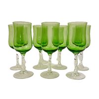 Front view of seven green stem glasses with clear bases and stems, arranged in a group.