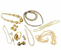 Photo of a collection of vintage faux pearl and beaded necklaces, brooches, and clip-on earrings arranged on a cloth surface, showing all items clearly.
