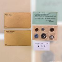 Photo of lot showing two US Treasury envelopes, a six-coin US proof set in plastic holder, a blue informational insert, and a Consortium Auction Services business card.