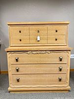 Front view of vintage light wood dresser showing two-tier drawer design with looped and decorative handles and carved accents.