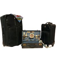 Front view of two different sized black rolling suitcases, vintage vanity case opened showing grooming tools inside, and colorful travel scarf