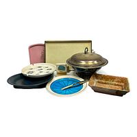 Single photo showing a vintage assortment of serving dishes and platters including a large silver-tone lidded dish, colorful ceramic trays, and a tray with multiple holes.