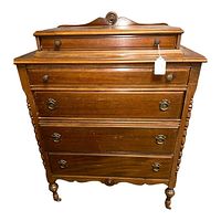 Front view of the vintage tall wooden dresser showing four drawers with metal pulls and carved details.