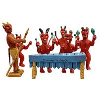 Front view of the set showing all six red devil-like wooden figurines with horns, one large with a spear, five smaller playing the blue marimba labeled 'Momba di dance'.
