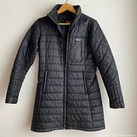 Front view of the black Patagonia Radalie Parka jacket on a hanger showing zippered front pockets, high collar, and Patagonia logo on chest pocket.