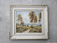 Full view of the framed original oil landscape painting showing birch trees, a pathway, and water in the background.