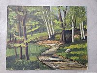 Photo of the front of the painting showing the forest landscape with river and dirt path