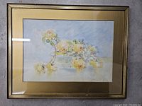 Full image of framed watercolor painting showing yellow roses in a glass vase, gold mat and frame visible.