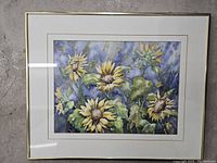 Front view of framed original watercolor painting depicting sunflowers with multiple blossoms and leaves in blue background.