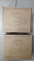 Two unopened cardboard boxes with printed outlines and labels indicating professional gel polish LED nail dryer lamps.