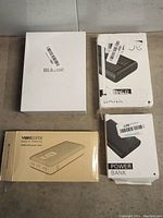 Four powerbanks in retail boxes on floor.