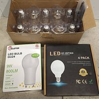 Box containing 8 loose LED light bulbs with other two sets of bulbs in original packaging visible below
