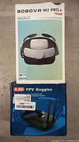 Photo of the BOBOVR M2 Pro+ VR headset box stacked on top of the 5.8G FPV goggles box showing both product boxes clearly.