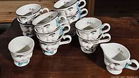 Full view of 12 ceramic tea set pieces stacked, showing face character on cups and creamer.