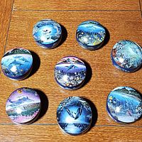 Top-down view of eight round music boxes with tropical oceanic artwork by Robert Lyn Nelson