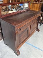 Front and angled view of the wooden buffet showing the tabletop, mirror, drawers, and cabinet doors.