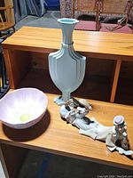 Photo shows all three decorative pieces on a wooden shelf: flower bowl, clown figurine, and blue vase.