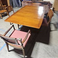 Full view of the vintage wooden drop leaf dining table with four matching chairs arranged around it, showing surface and structure.