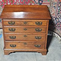 Front view of wooden end table showing four drawers with brass hardware and some surface scratches.