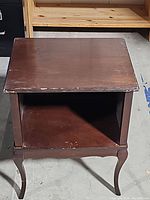 Top view of the vintage side table showing scratches, wear, and the open storage compartment underneath the tabletop.