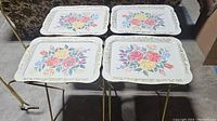 Four folding trays set up side by side showing top surfaces and legs.