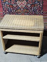 Wicker rolling cart showing front view with two shelves and caster wheels.