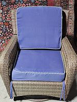 Top-down view of the wicker chair with blue back and seat cushions showing white rope trim on cushions and tied corners.