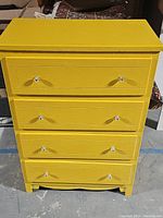 Full frontal view of yellow dresser with four drawers and crystal-like knobs.