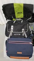 Photo showing stacked Vega, Timbuk2, and Tommy Hilfiger laptop bags highlighting colors and brand logos