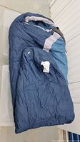 Blue and grey mummy-shaped sleeping bag laid out flat showing overall design and shape.