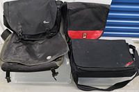 Four large laptop/photo bags including Lowepro, Crumpler, Domke, and Chrome on a chair, all showing some dust from storage.