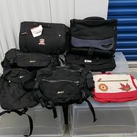 Nine laptop backpacks arranged showing various brands and some with Olympic Canada vintage patches and unique design details