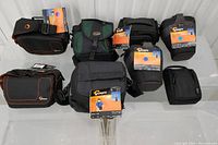 Eight LOWEPRO camera bags including models Cirrus TLZ15, Altus 140, Clips 110, Impulse 110, and EX 120, six with new tags.