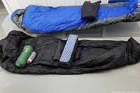 Photo showing the blue ASOLO Quadratherm insulated mummy sleeping bag with hood and black sleeping bag liner with green and blue accessory bags.