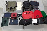 Overview of assorted bags, gloves, hats, pouches and first aid kit on plastic crates.