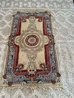 Full view of the rectangular Indian rug on carpeted floor, showing overall pattern and fringed edges.