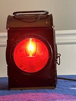 Front view showing lit red glass with bulb inside and Sherwood's 1944 marking on top handle.