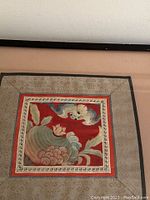 Frontal image showing overall silk embroidery panel framed, with bat and lotus design on red fabric and bordered by intricate textile trim.