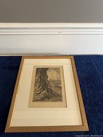 Full view of the framed antique etching showing the artwork, matting, and wooden frame against a dark blue background.