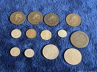 Top view of all coins laid on blue cloth showing variety in size and monarch profiles